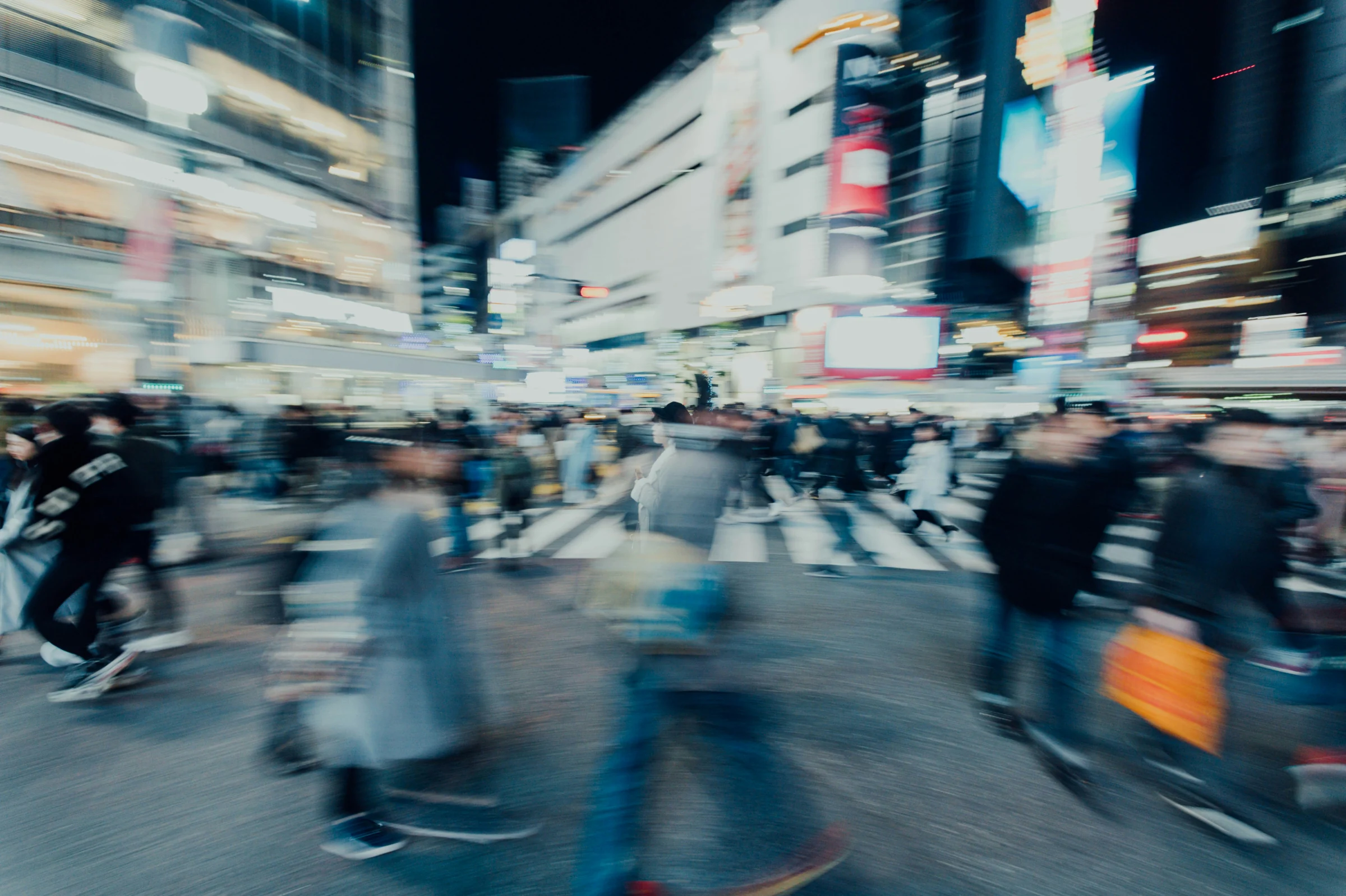 People crossing Shibuya at night, photographed in intentional motion blur by CHUTTERSNAP.